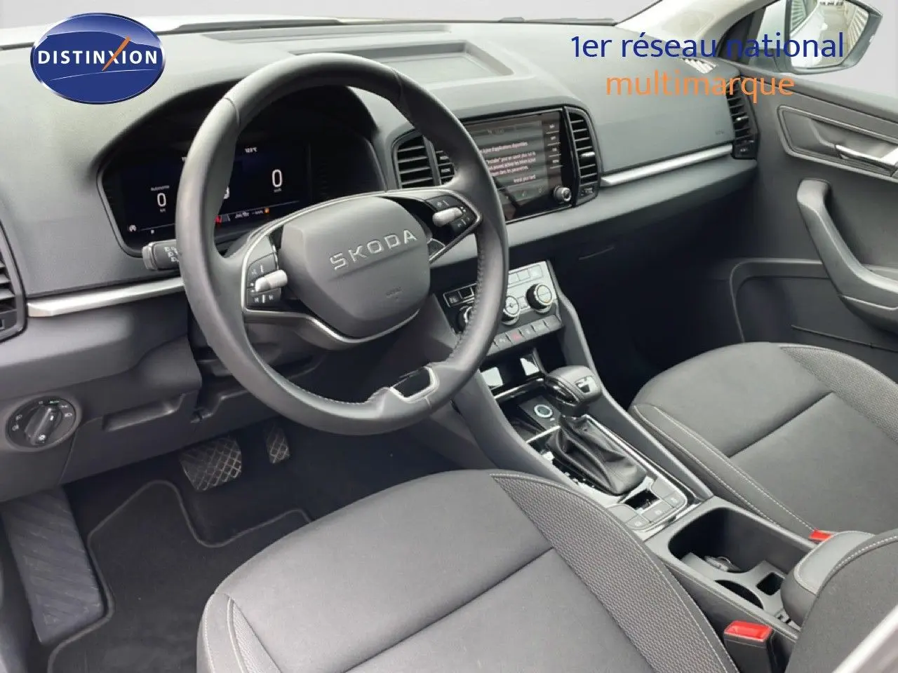 Vue intérieure côté conducteur du Skoda Karoq 2025, tableau de bord et volant noir avec écran digital et console centrale.