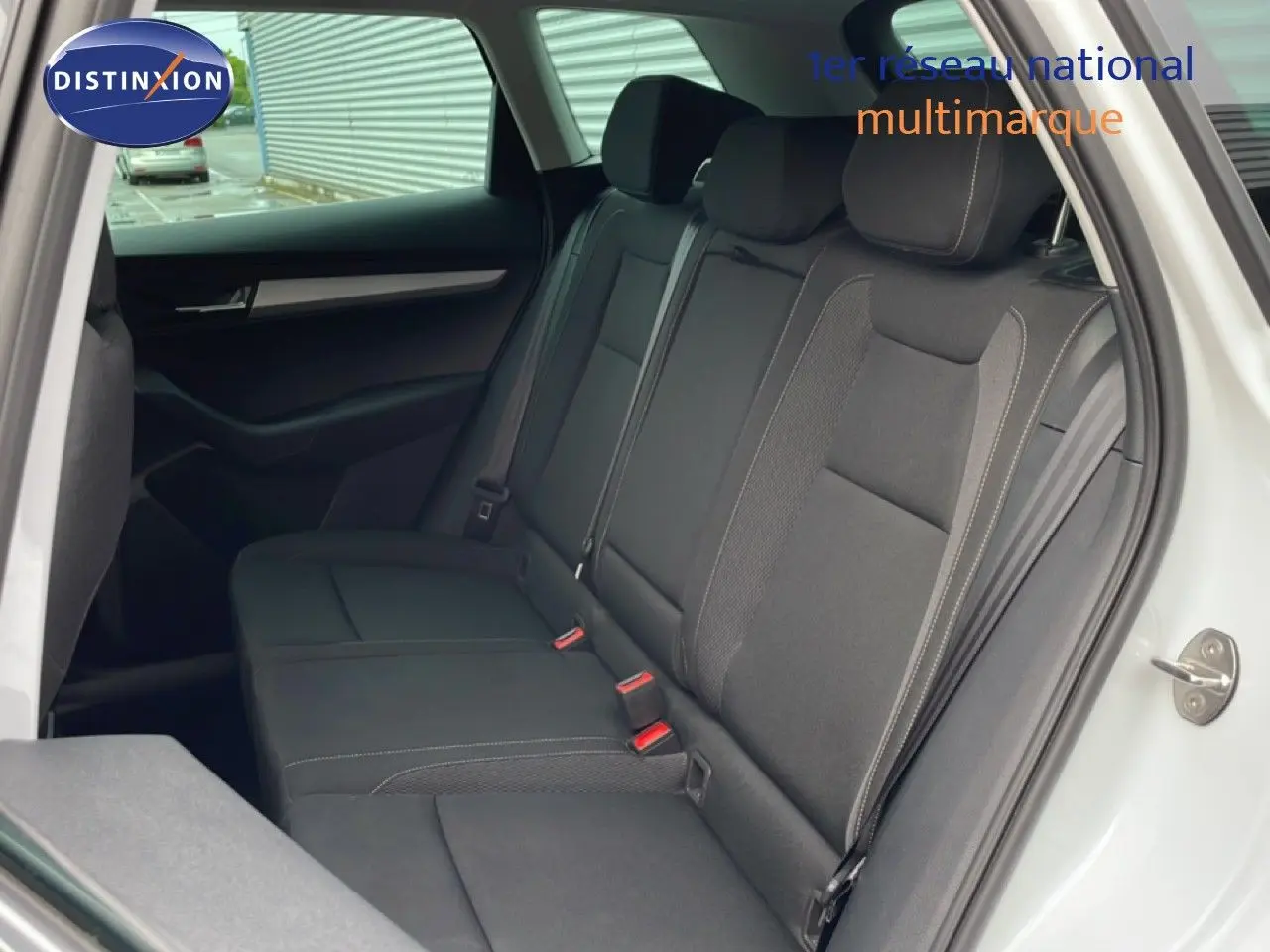 Vue intérieure côté gauche montrant la banquette arrière en tissu noir du Skoda Karoq blanc glacier 2025.