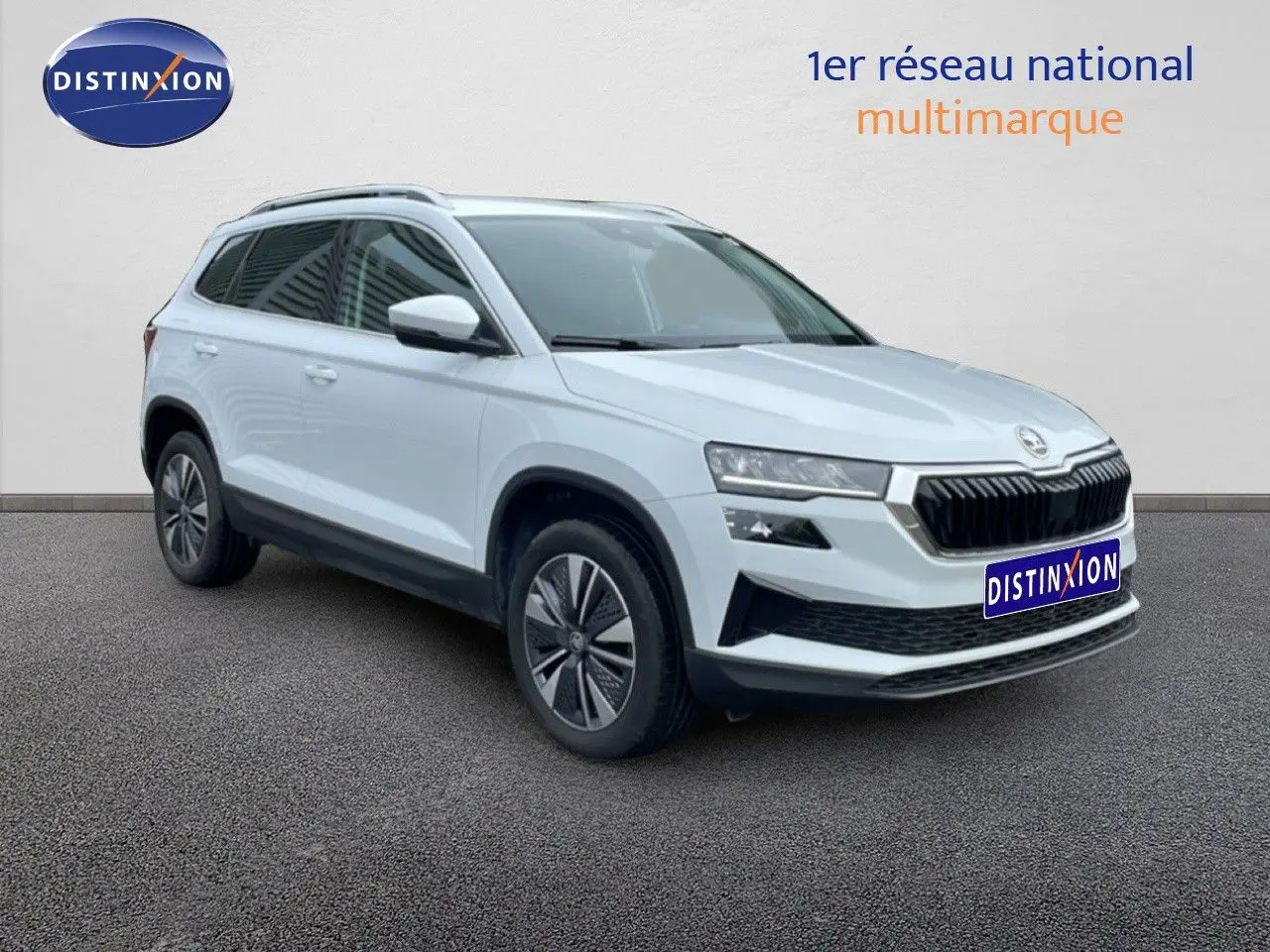 Vue 3/4 avant droit d’un Skoda Karoq blanc glacier avec calandre noire et jantes bi-ton.