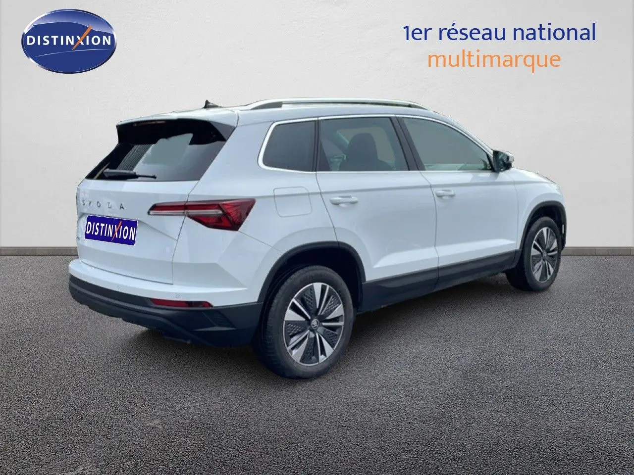Vue 3/4 arrière droite du Skoda Karoq blanc glacier avec jantes bi-ton et toit noir contrasté.
