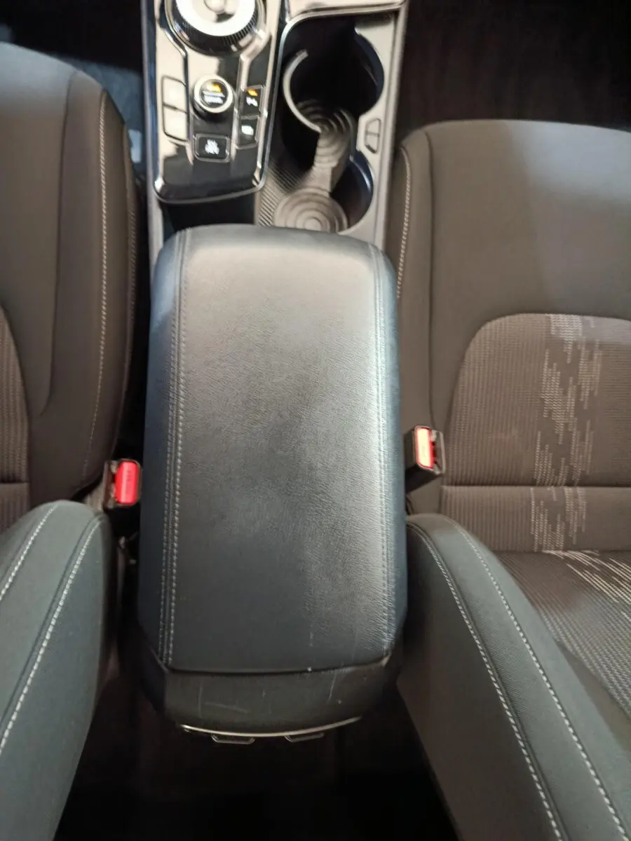 Vue plongeante sur l'accoudoir central noir et les sièges avant gris du Kia Sportage hybride rechargeable 2022.