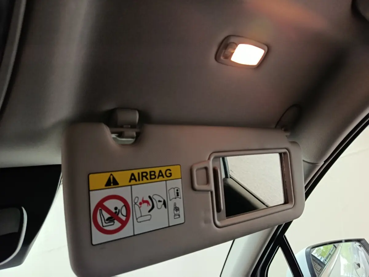Détail intérieur du pare-soleil côté conducteur du Kia Sportage blanc 2022 avec miroir et avertissement airbag visible.