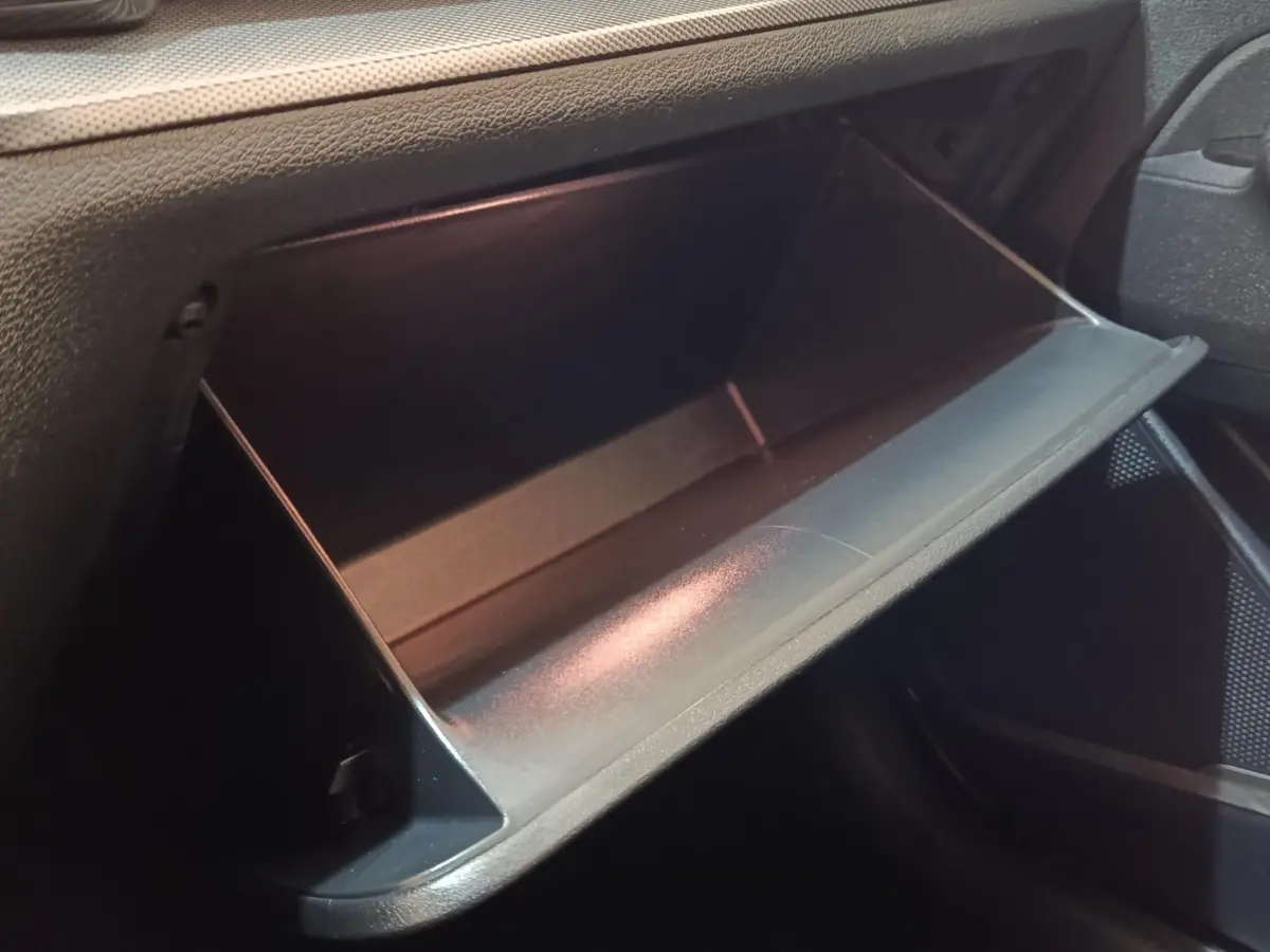 Gros plan sur la boîte à gants ouverte côté passager du Kia Sportage blanc, intérieur noir texturé.