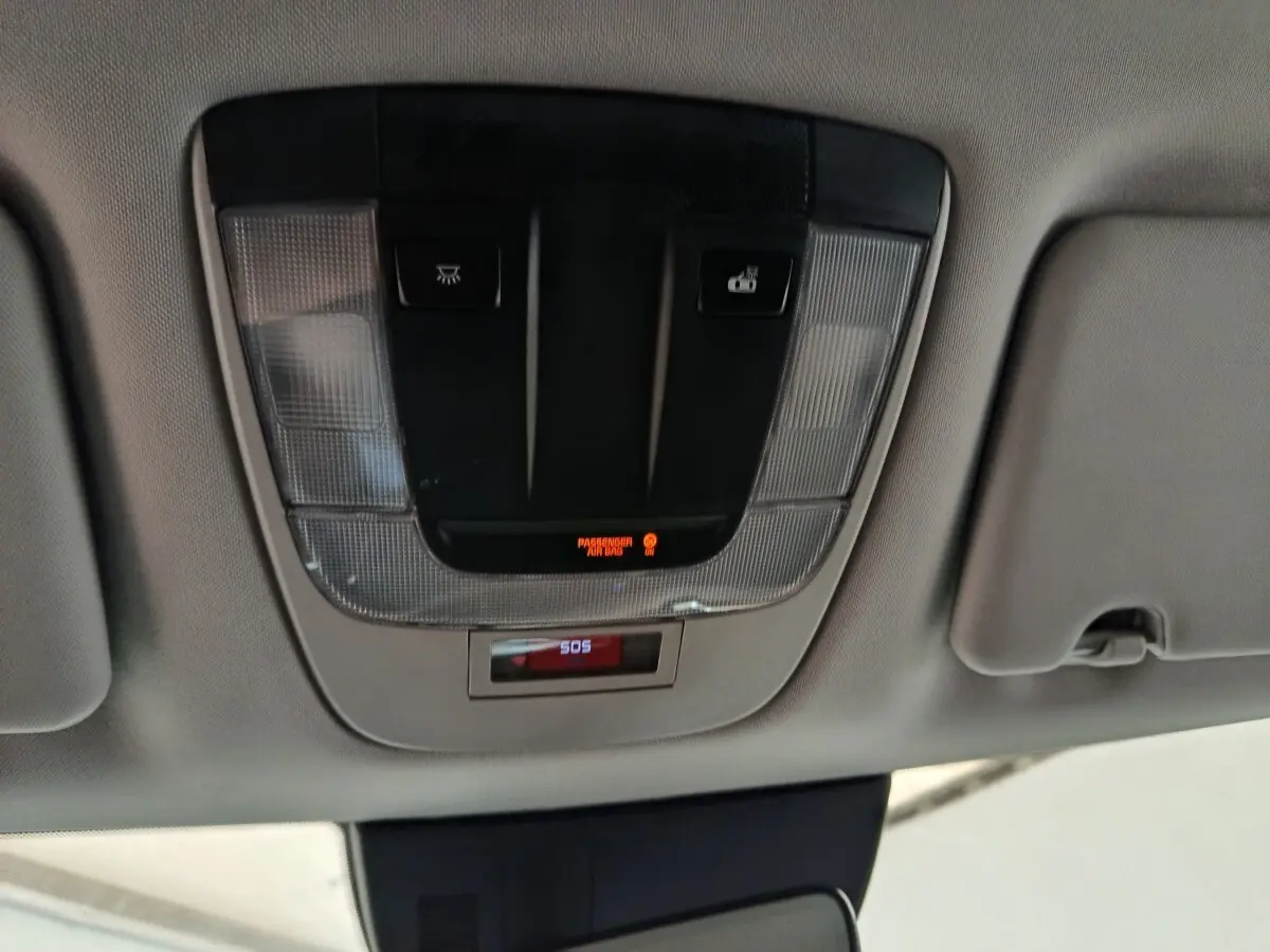 Vue en gros plan du plafonnier gris avec boutons d'éclairage et alerte SOS dans un Kia Sportage blanc 2022.