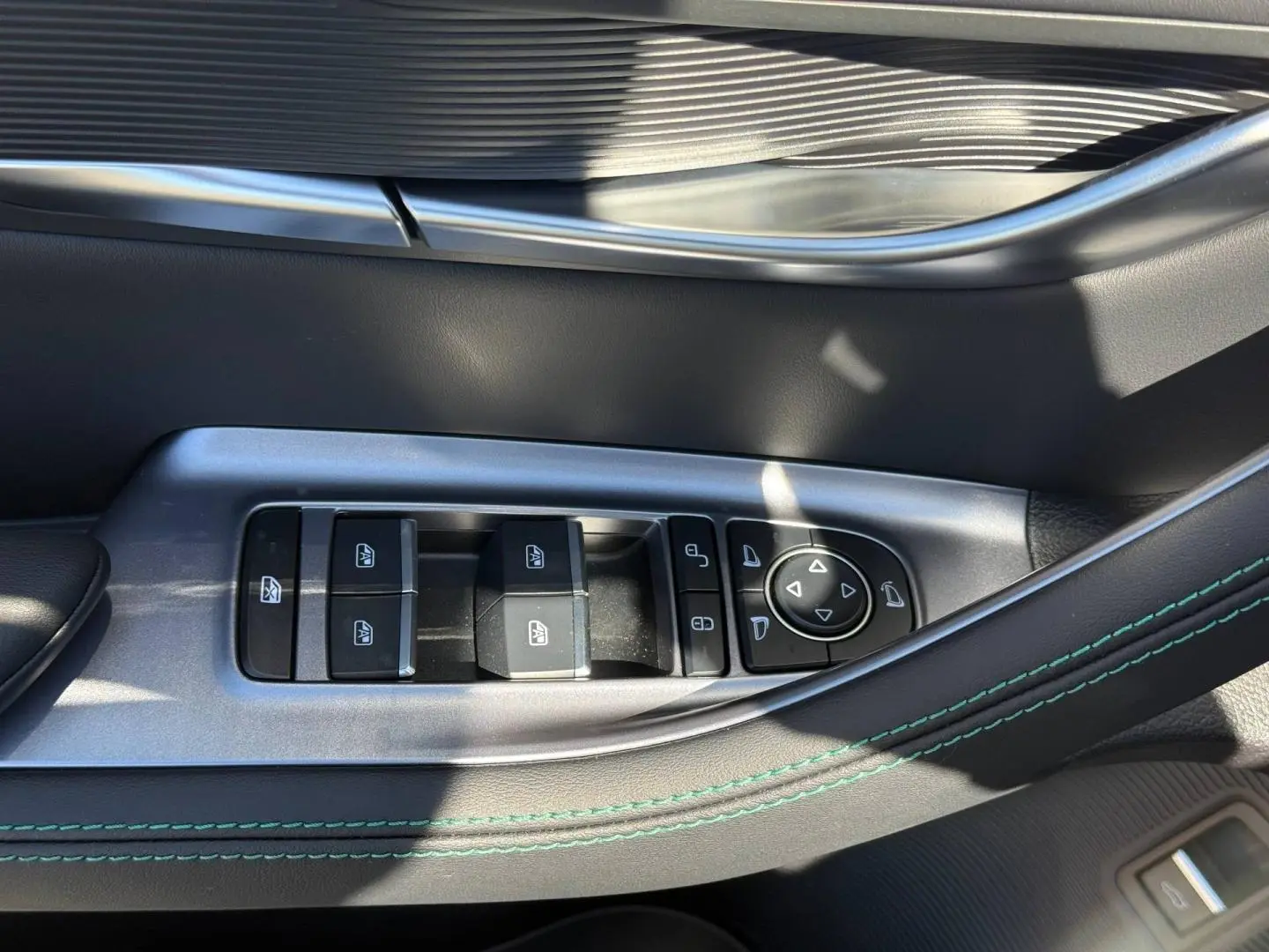 Gros plan sur la commande des vitres côté gauche du BYD SEAL U 1.5 DM-i 218ch Boost en intérieur noir avec surpiqûres vertes.