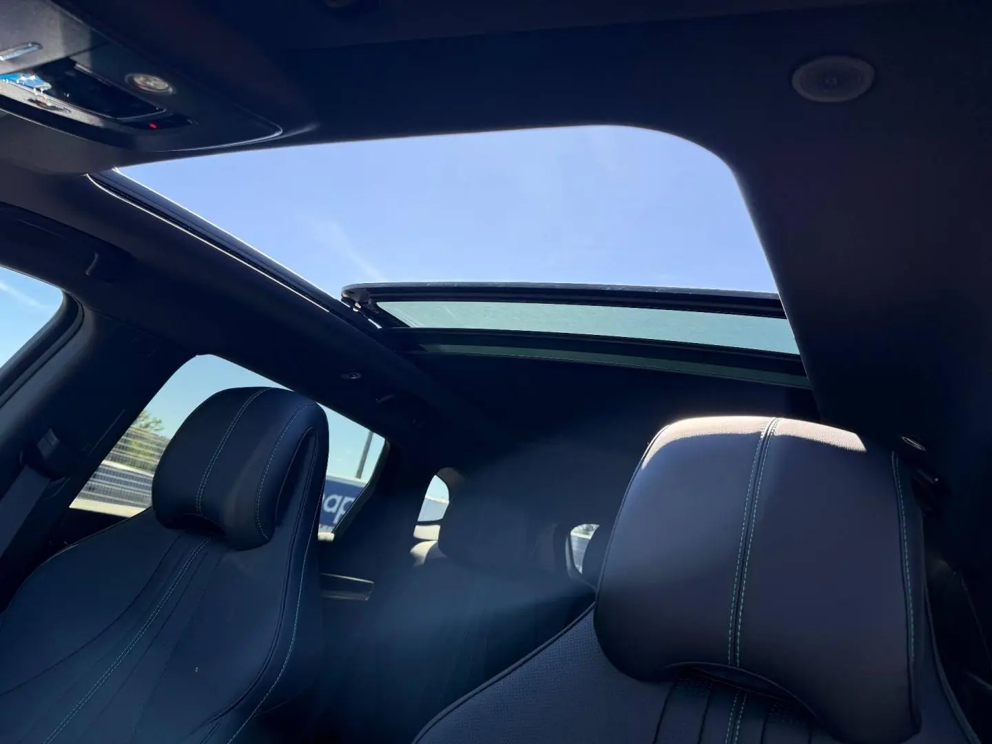 Intérieur du BYD SEAL U 2026 vu de l'arrière, toit panoramique en verre ouvert laissant entrer la lumière.