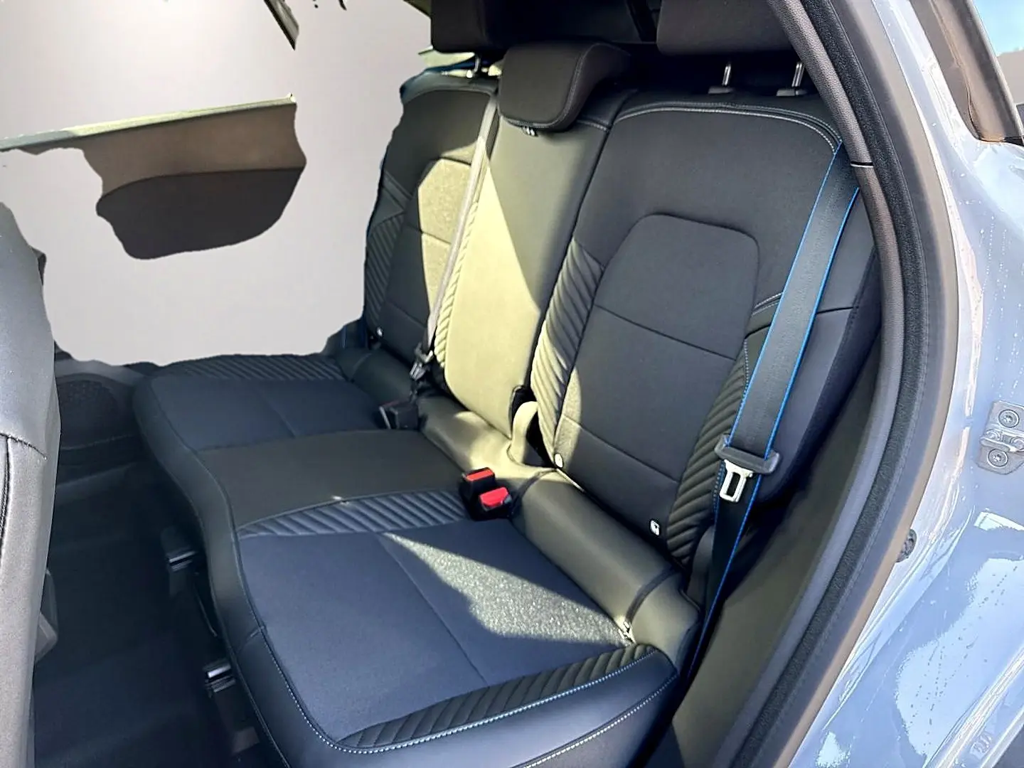Vue côté droit de la banquette arrière gris foncé avec surpiqûres bleues du Renault Symbioz 2026 gris rafale.