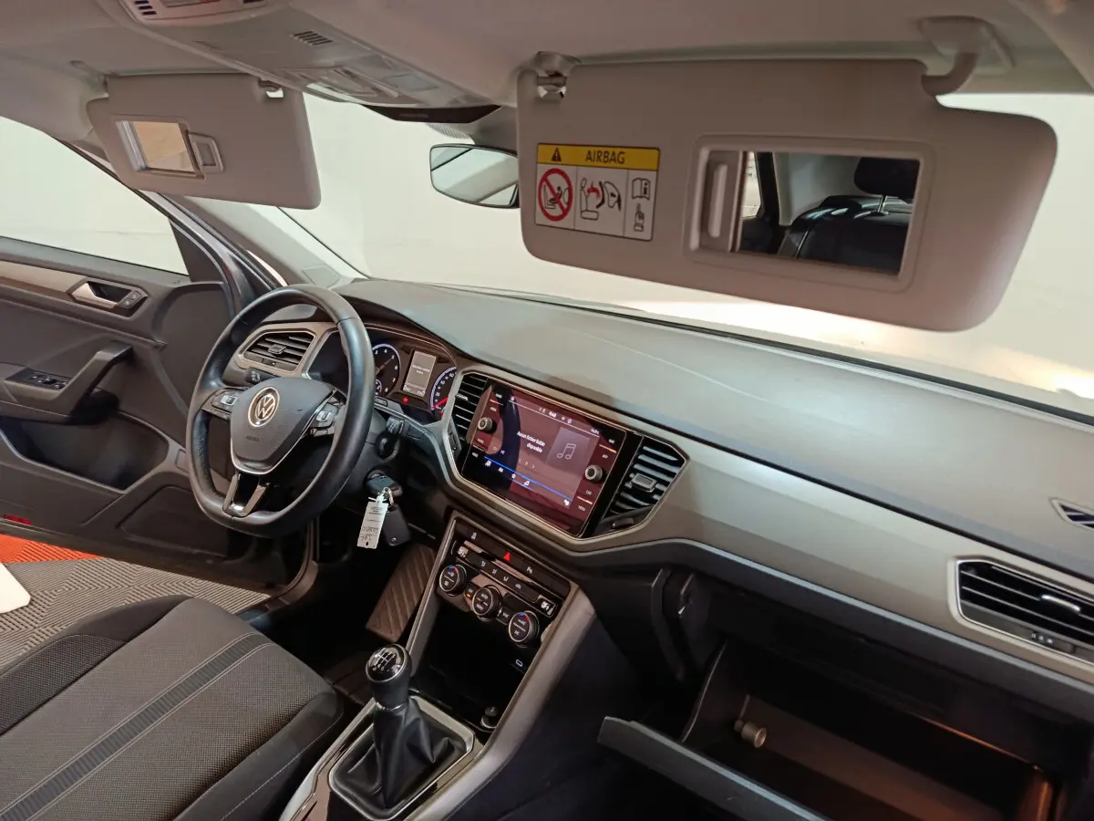 Intérieur Volkswagen T-Roc 2021 côté conducteur, tableau de bord noir avec écran tactile et boîte manuelle visible.