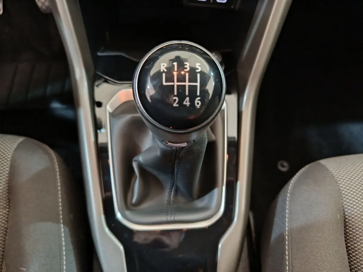 Le levier de vitesses manuel noir du Volkswagen T-Roc 1.0 TSI 110 Lounge Business vu de dessus entre les sièges gris.