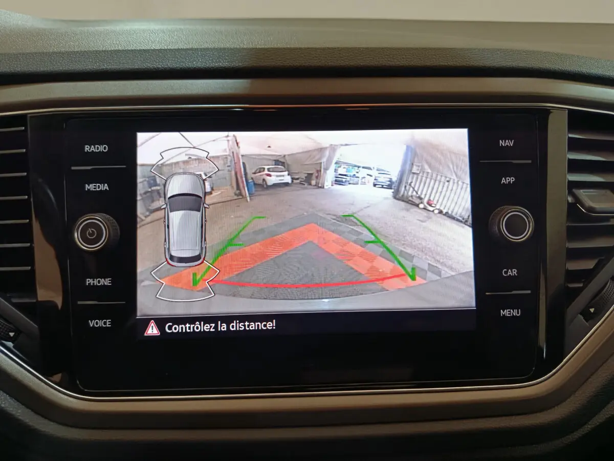 Écran tactile intérieur du Volkswagen T-Roc gris foncé montrant la caméra de recul avec guidage de trajectoire coloré.