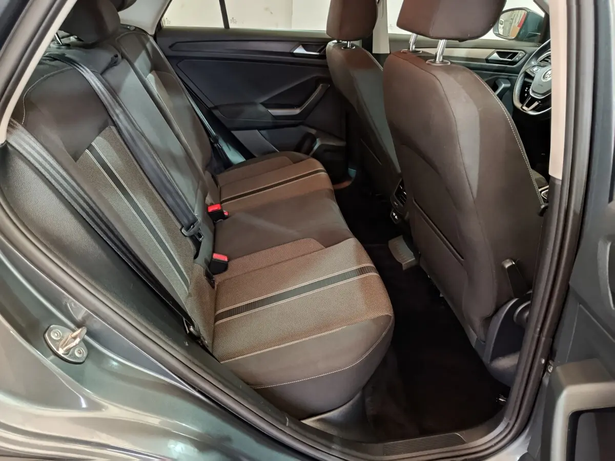 Vue intérieure arrière droite du Volkswagen T-Roc gris foncé, montrant la banquette tissu avec bandes centrales contrastées.