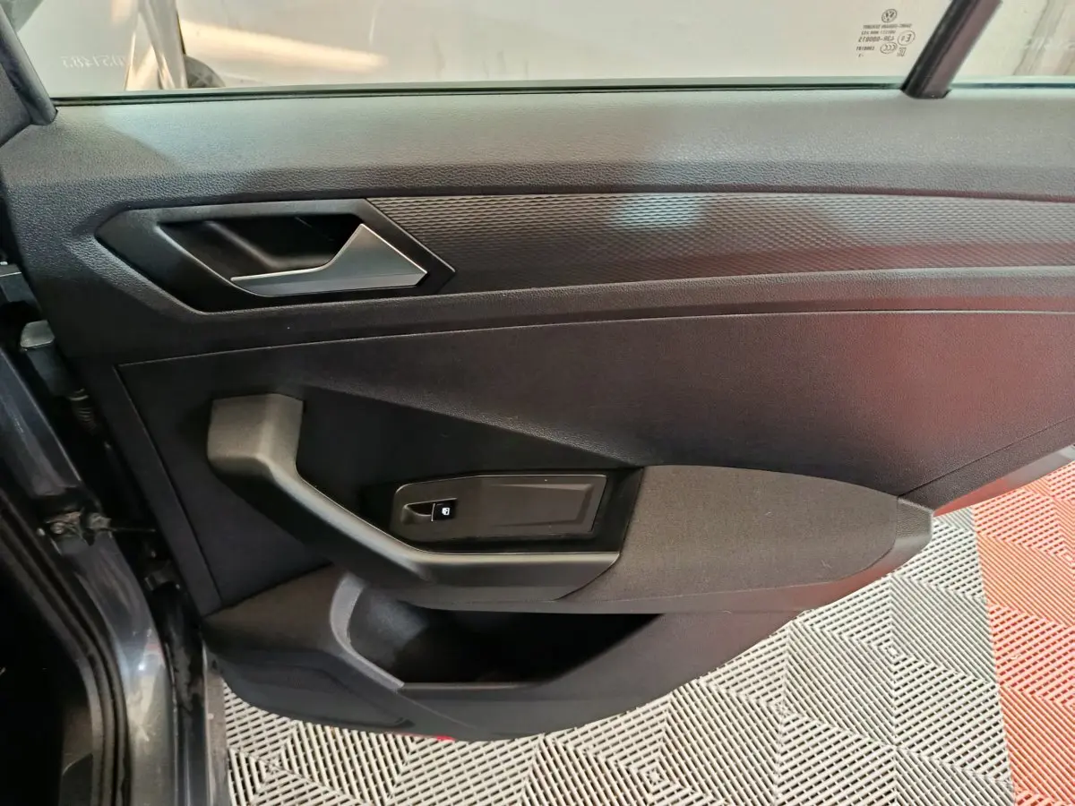 Vue rapprochée de la porte avant gauche grise foncée du Volkswagen T-Roc 2021 avec poignée et commande de vitre électrique.
