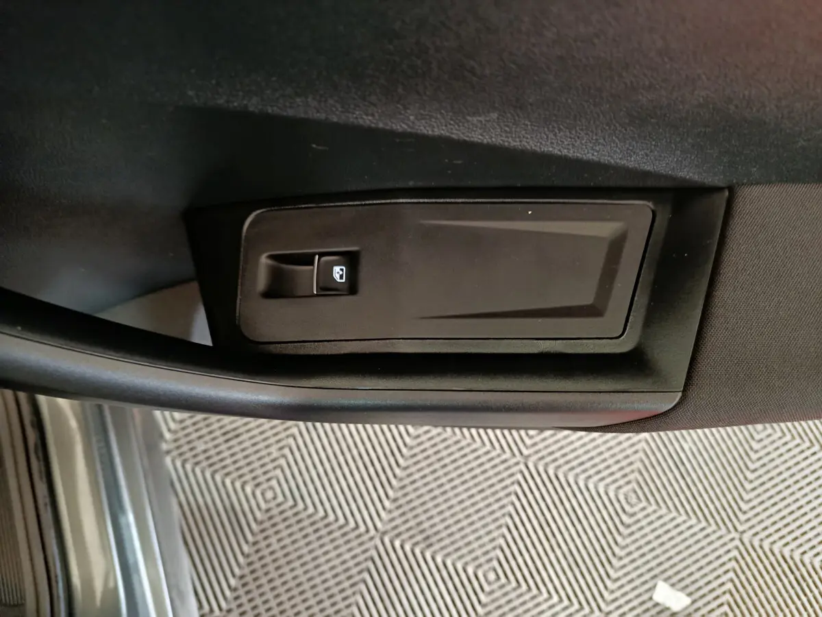 Poignée intérieure de porte côté gauche du Volkswagen T-Roc gris foncé, avec bouton de verrouillage des vitres.