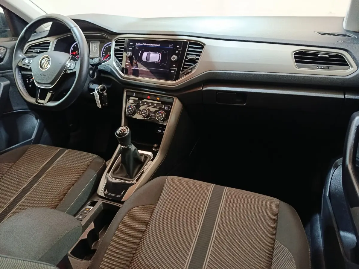 Intérieur du Volkswagen T-Roc 2021 vue côté conducteur, volant cuir, tableau de bord avec écran tactile et boîte manuelle.