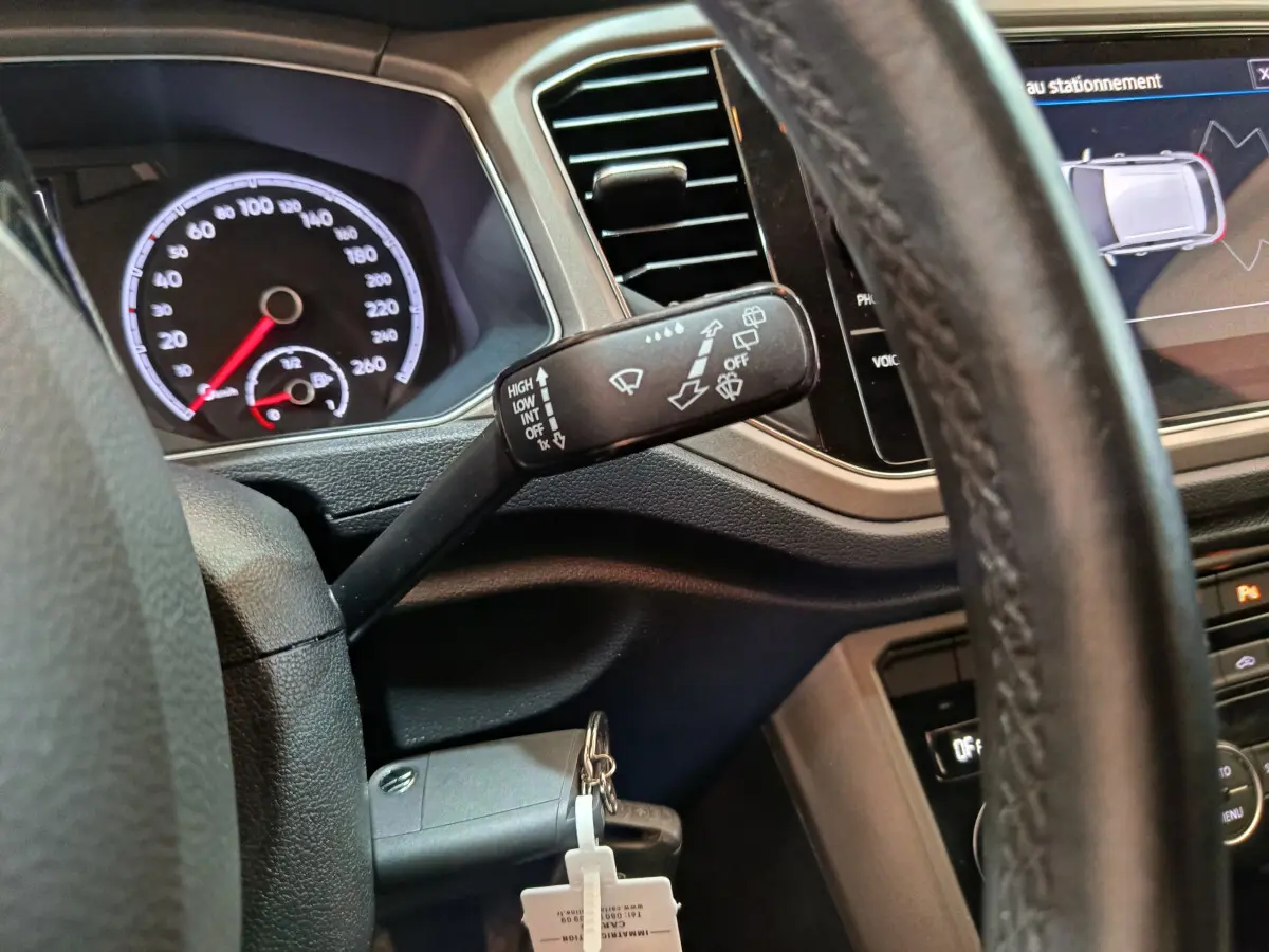 Vue intérieure rapprochée du volant et du commodo d’essuie-glace du Volkswagen T-Roc 2021, avec tableau de bord et écran tactile visibles.