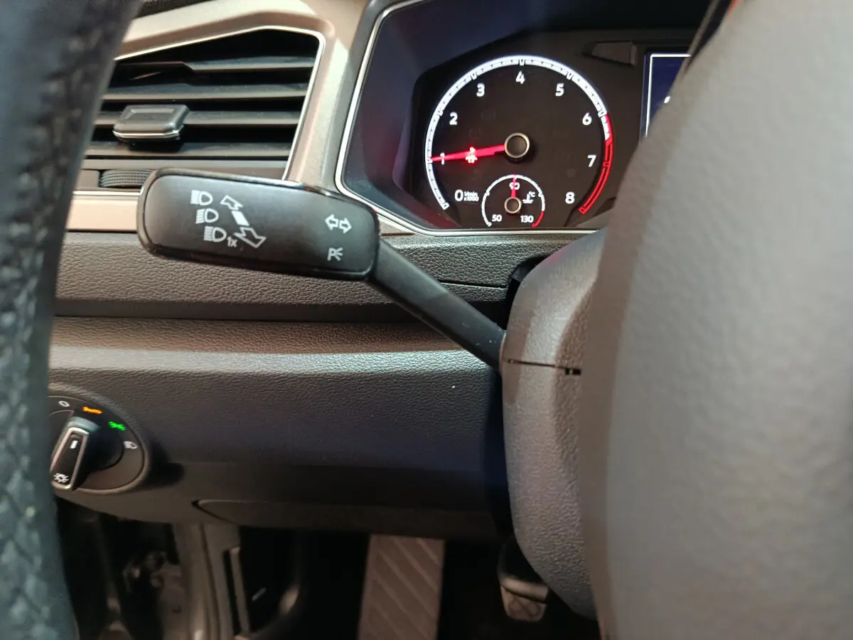 Détail du tableau de bord et du commodo gauche du Volkswagen T-Roc 1.0 TSI gris foncé, avec compte-tours visible.