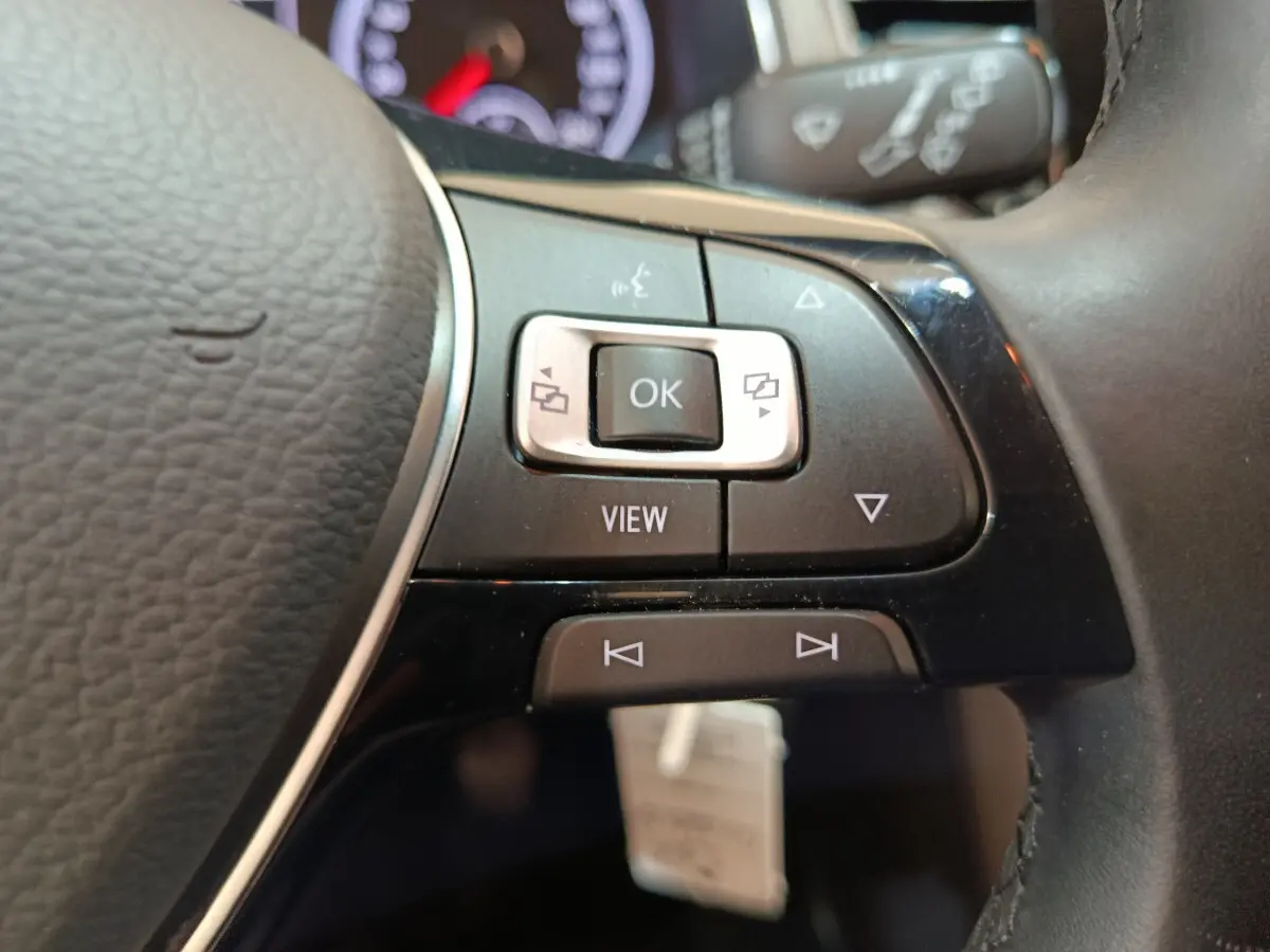 Gros plan sur les commandes multifonctions du volant cuir noir du Volkswagen T-Roc 2021 gris foncé.