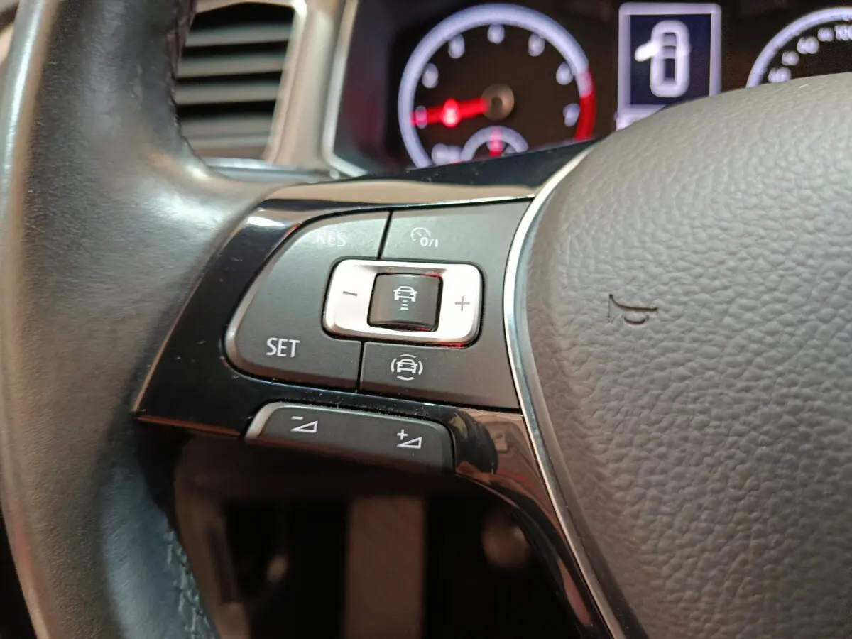 Gros plan sur les commandes du volant cuir du Volkswagen T-Roc 2021, avec tableau de bord numérique en arrière-plan.