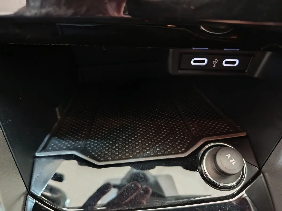 Prise 12V et ports USB doubles dans la console centrale du Volkswagen T-Roc 1.0 TSI gris foncé, vue intérieure rapprochée.