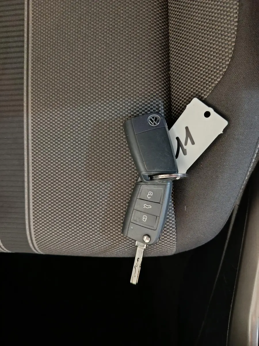 Clé Volkswagen posée sur un siège tissu gris foncé à motifs, intérieur du Volkswagen T-Roc 2021 visible partiellement.