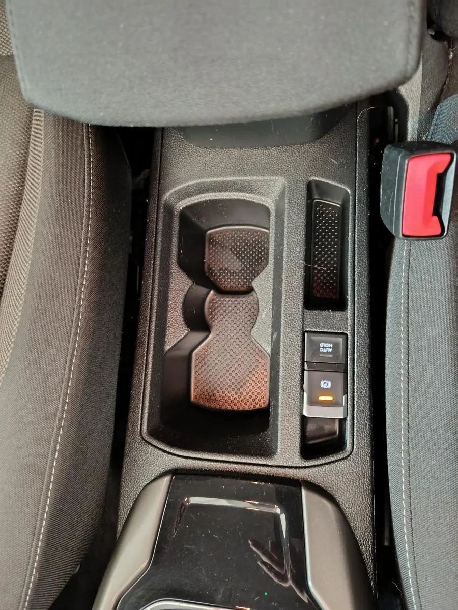 Gros plan sur la console centrale noire du Volkswagen T-Roc 2021, avec porte-gobelets et frein à main électrique.