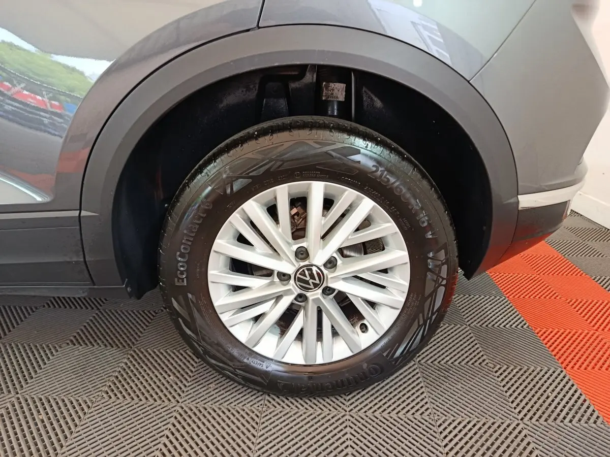 Gros plan sur la roue arrière droite grise foncée d'un Volkswagen T-Roc 2021 avec jante alliage à rayons fins blancs.