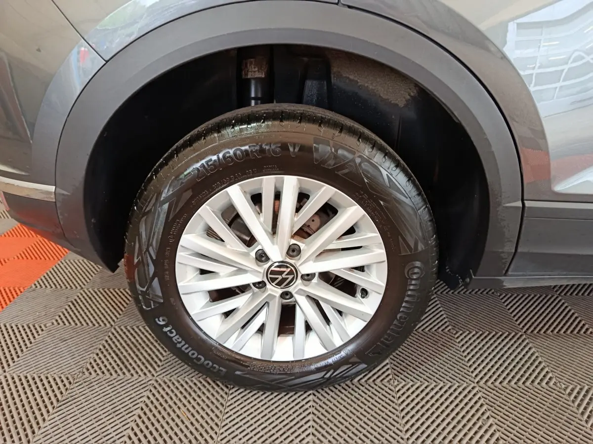 Gros plan sur la roue avant gauche gris foncé du Volkswagen T-Roc 1.0 TSI 110 Lounge Business avec jante alliage blanche.