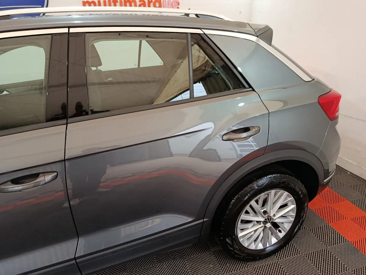 Vue côté droit arrière du Volkswagen T-Roc gris foncé mettant en valeur la roue et les lignes de caisse.
