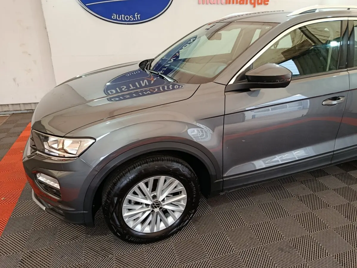Vue 3/4 avant droit d'un Volkswagen T-Roc gris foncé avec jante alliage et rétroviseur noir brillant.