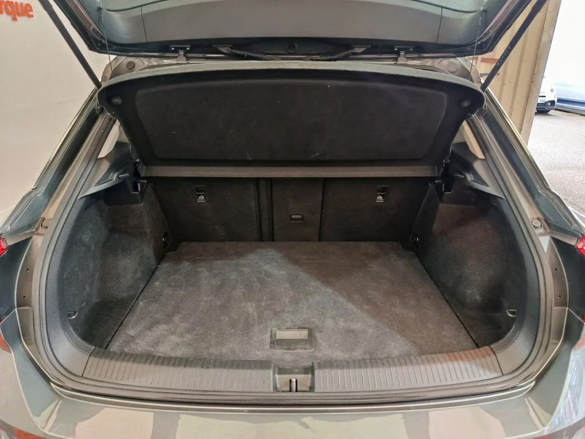 Coffre ouvert vu de l'arrière d'un Volkswagen T-Roc gris foncé, montrant un espace de chargement propre et spacieux.