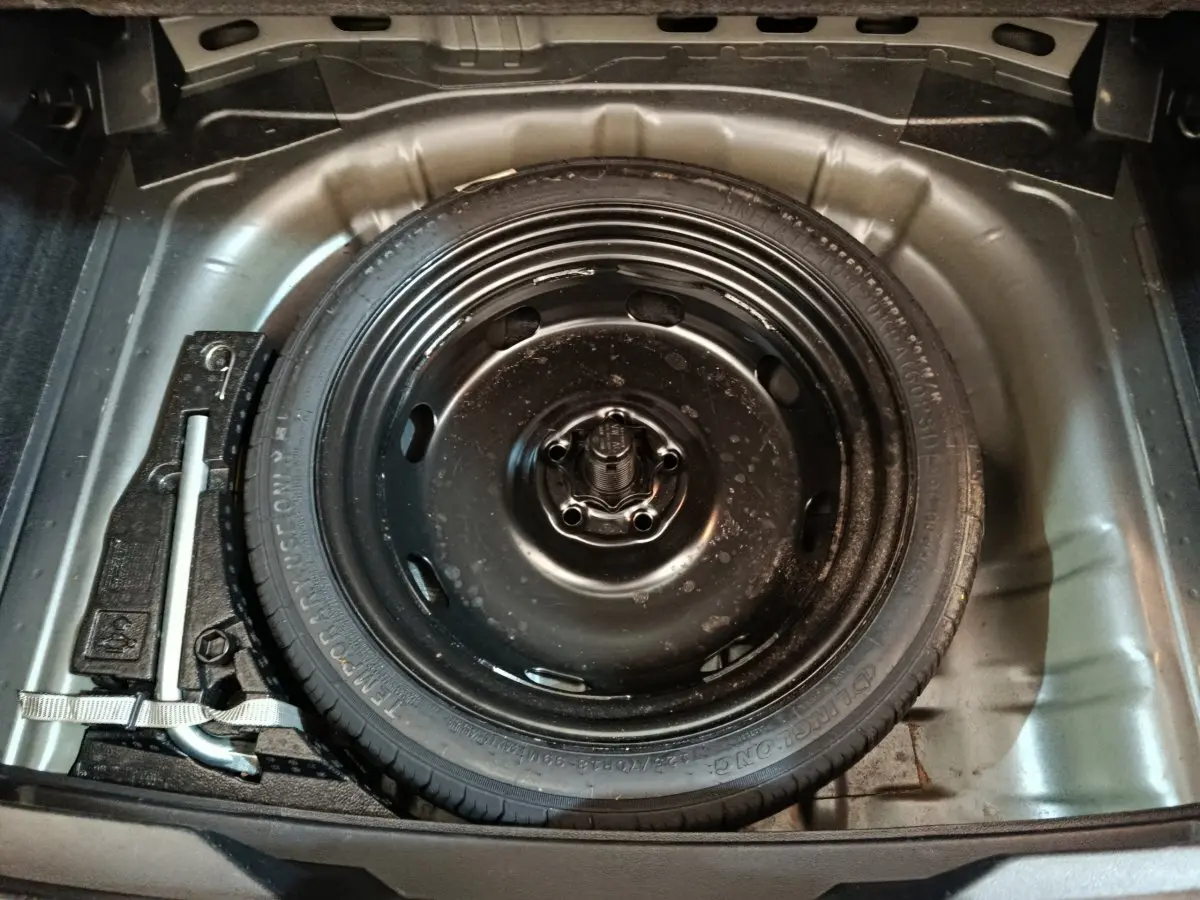 Vue rapprochée de la roue de secours noire dans le coffre gris foncé du Volkswagen T-Roc 1.0 TSI 110 Lounge Business 2021.