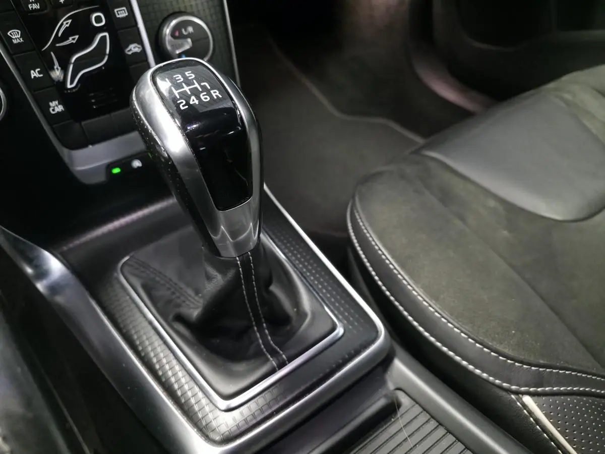 Levier de vitesses manuel en cuir perforé avec surpiqûres beige dans l'habitacle noir du Volvo V40 R-Design.