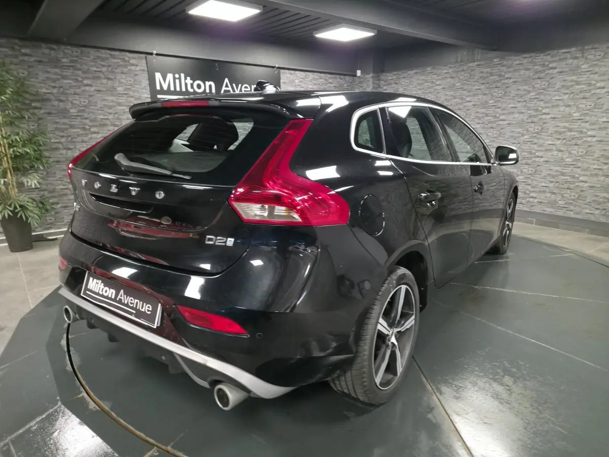 Vue 3/4 arrière droite d'une Volvo V40 D2 noire avec jantes alliage et double sortie d'échappement chromée.