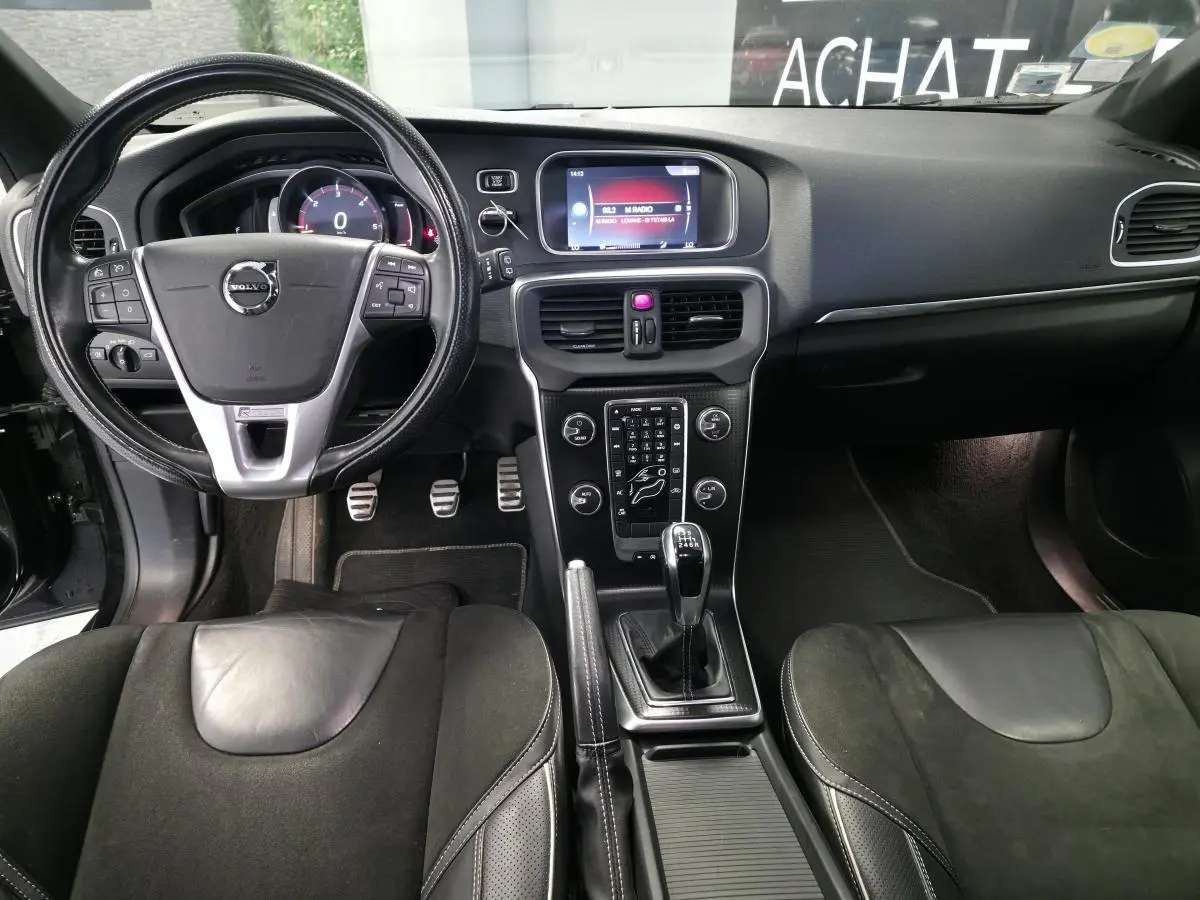 Vue intérieure avant de la Volvo V40 D2 R-Design 2019, volant cuir perforé, levier manuel et console centrale noire.