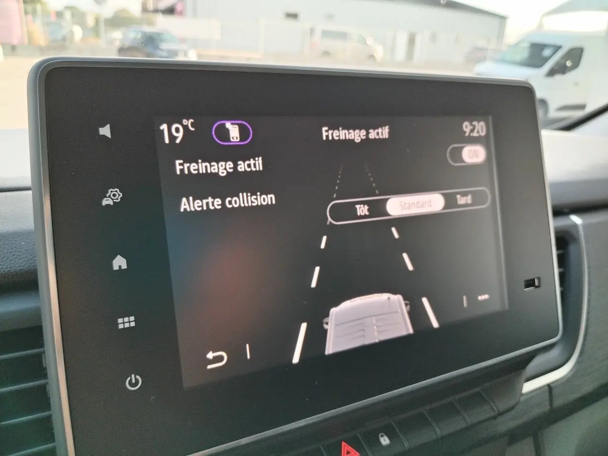 Écran tactile intérieur du Nissan Primastar 2025 montrant l'alerte collision et freinage actif à 19°C.