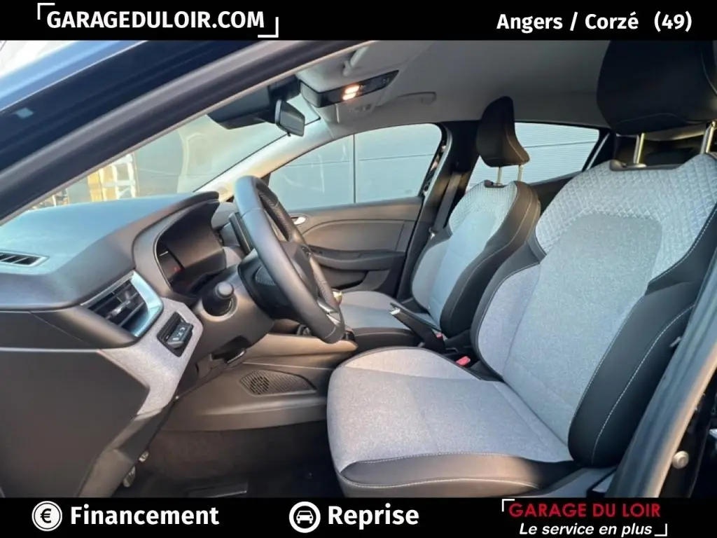 Vue intérieure côté conducteur de la Renault Clio noire 2025 avec sièges tissu clair et volant multifonctions cuir synthétique.