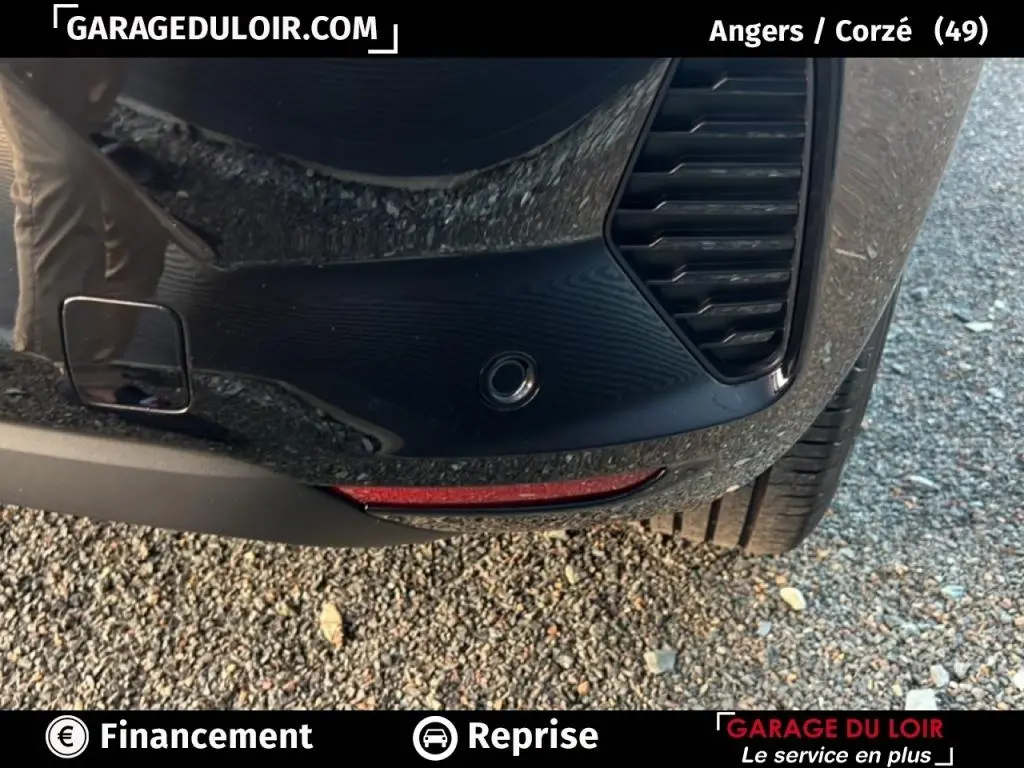 Gros plan sur le pare-chocs arrière droit noir de la Renault Clio 2025 avec capteur de stationnement et feu réfléchissant rouge.