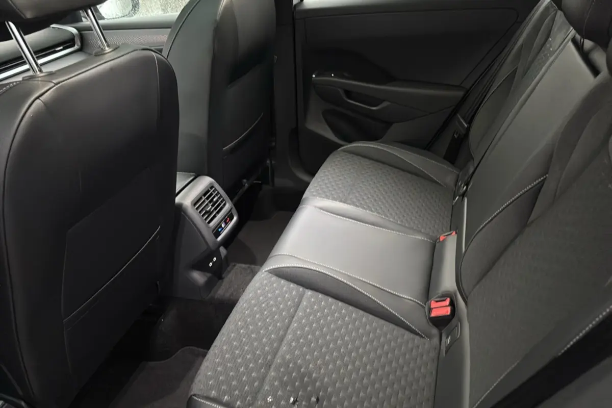 Vue intérieure arrière côté droit du Volkswagen T-Roc 2026, sièges tissu noir avec surpiqûres grises et aérateurs centraux.