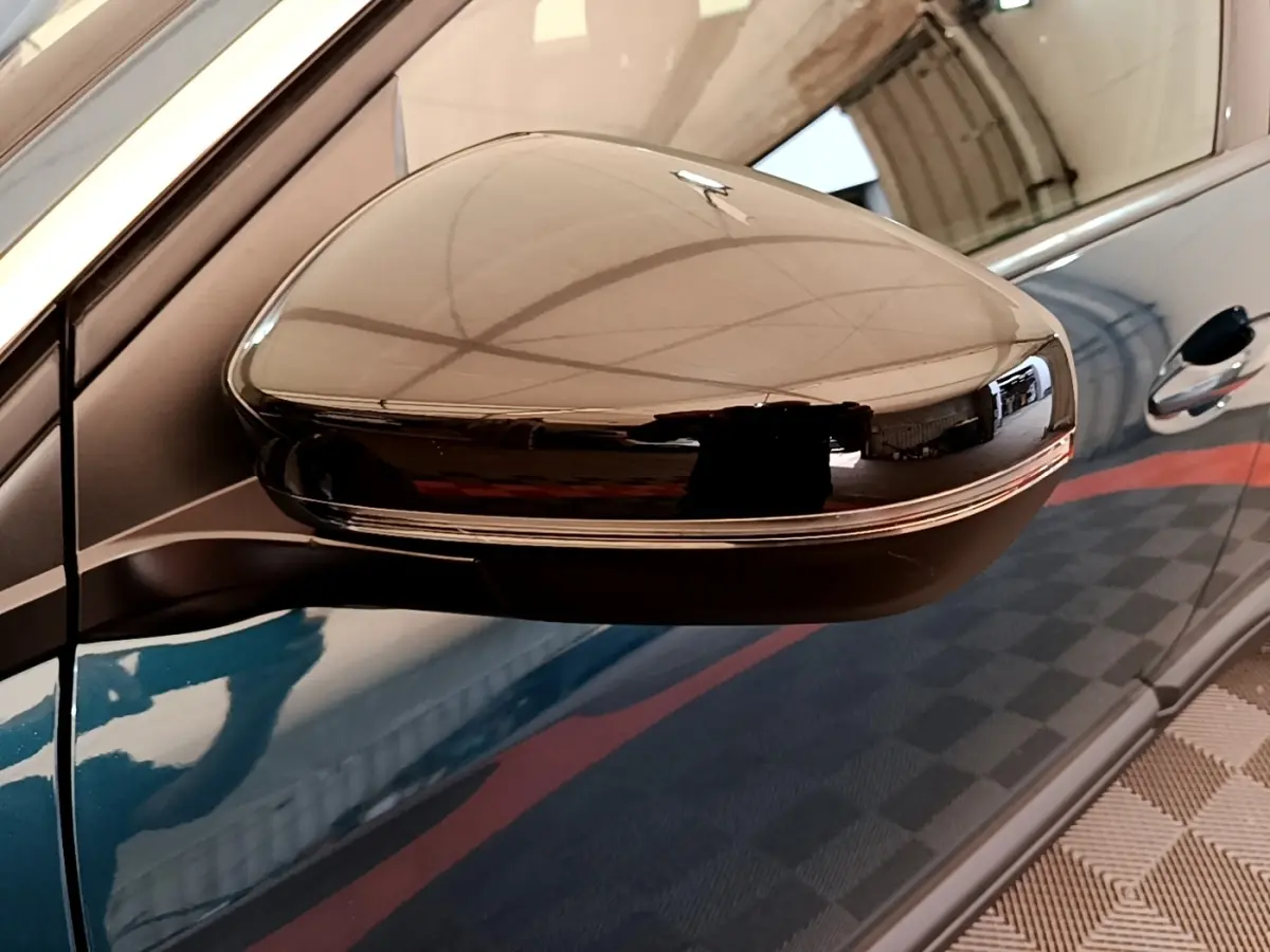Rétroviseur droit noir brillant sur Peugeot 3008 bleu, vue rapprochée côté conducteur avec reflet intérieur.
