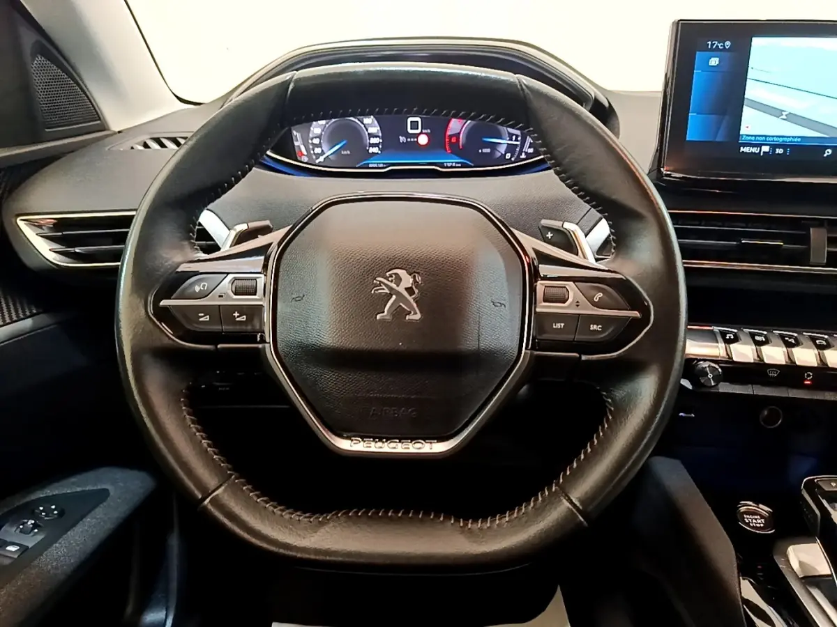 Vue intérieure centrée sur le volant cuir noir de la Peugeot 3008 avec tableau de bord digital et écran tactile.
