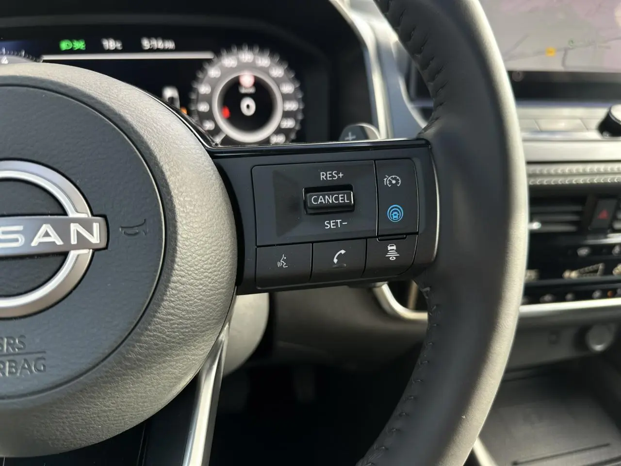 Gros plan sur le volant cuir noir du Nissan Qashqai 2025 avec commandes de régulateur de vitesse et tableau de bord numérique.