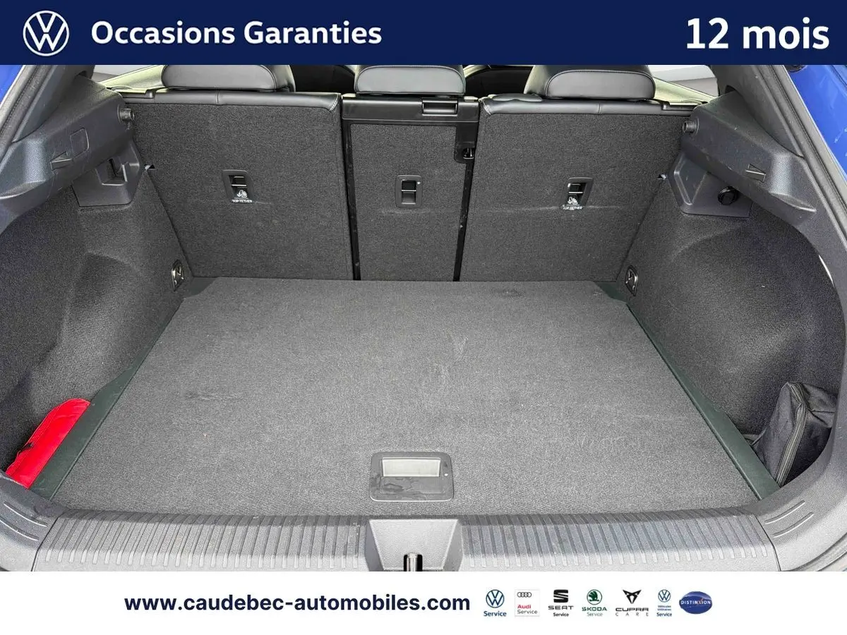 Coffre ouvert du Volkswagen T-Roc bleu, vue arrière montrant l’espace de chargement et la banquette rabattable.