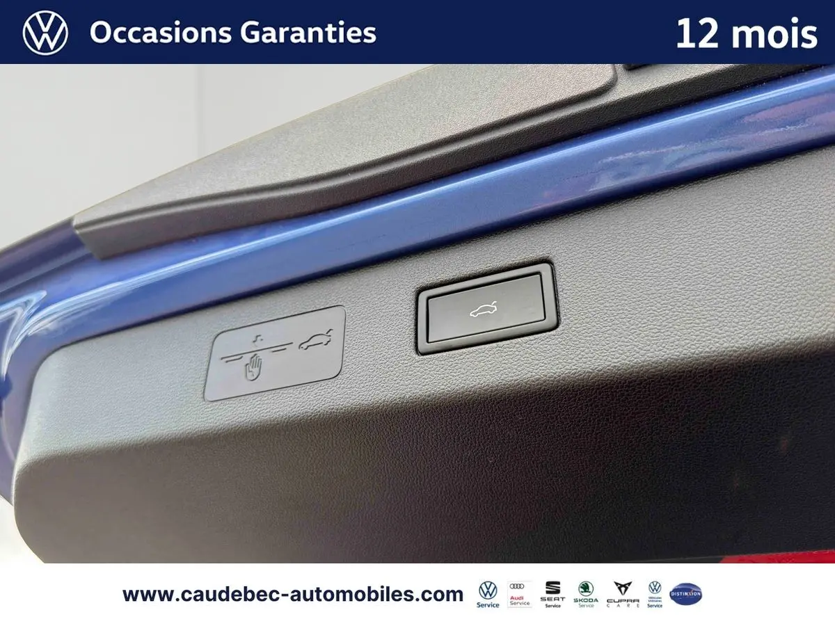 Bouton d'ouverture électrique du coffre sur la porte arrière d'un Volkswagen T-Roc bleu, vue en gros plan.