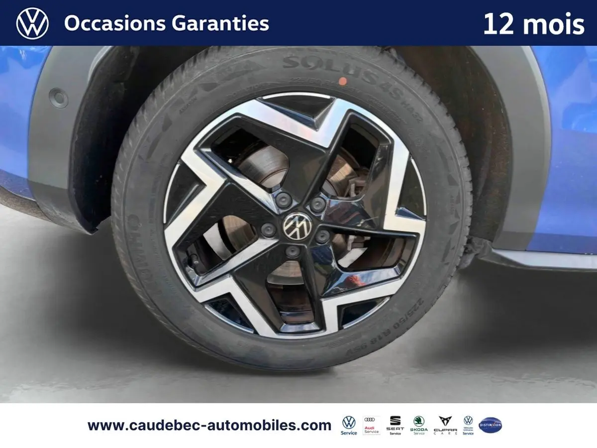 Gros plan sur la jante alliage Coventry noire et brillante du côté gauche d’un Volkswagen T-Roc bleu métallisé.