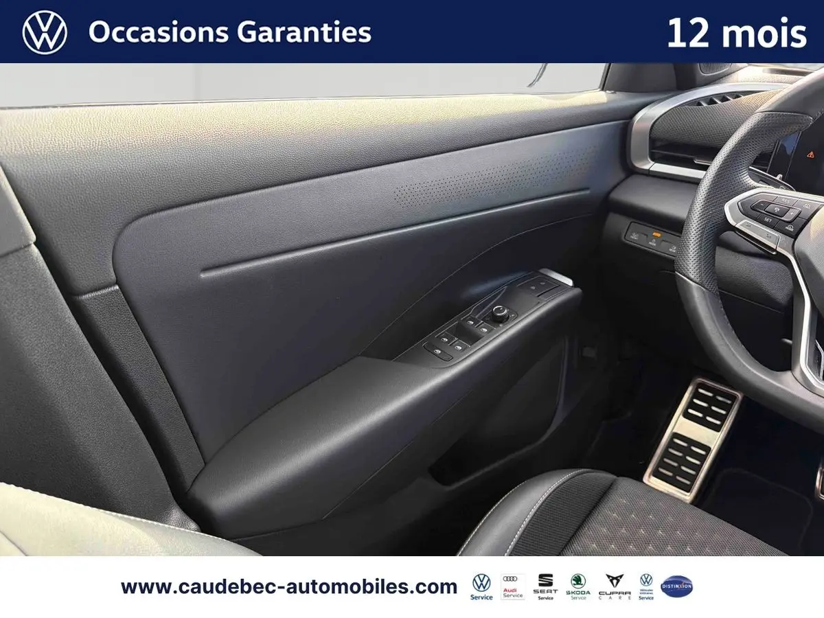 Vue intérieure côté conducteur du Volkswagen T-Roc 2026, montrant la portière noire avec commandes des vitres et partie du volant cuir.