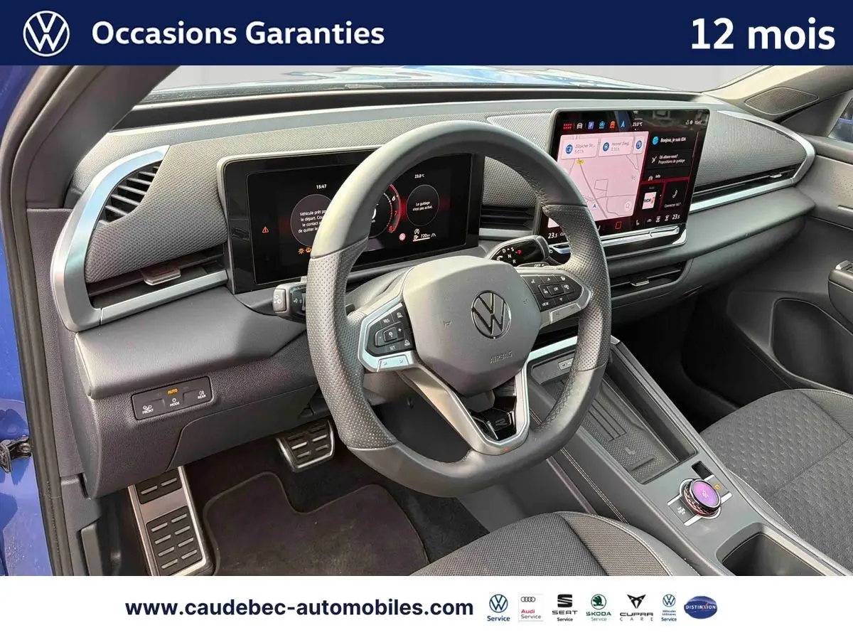 Vue intérieure côté conducteur du Volkswagen T-Roc bleu 2026, volant multifonction et écran tactile visibles.