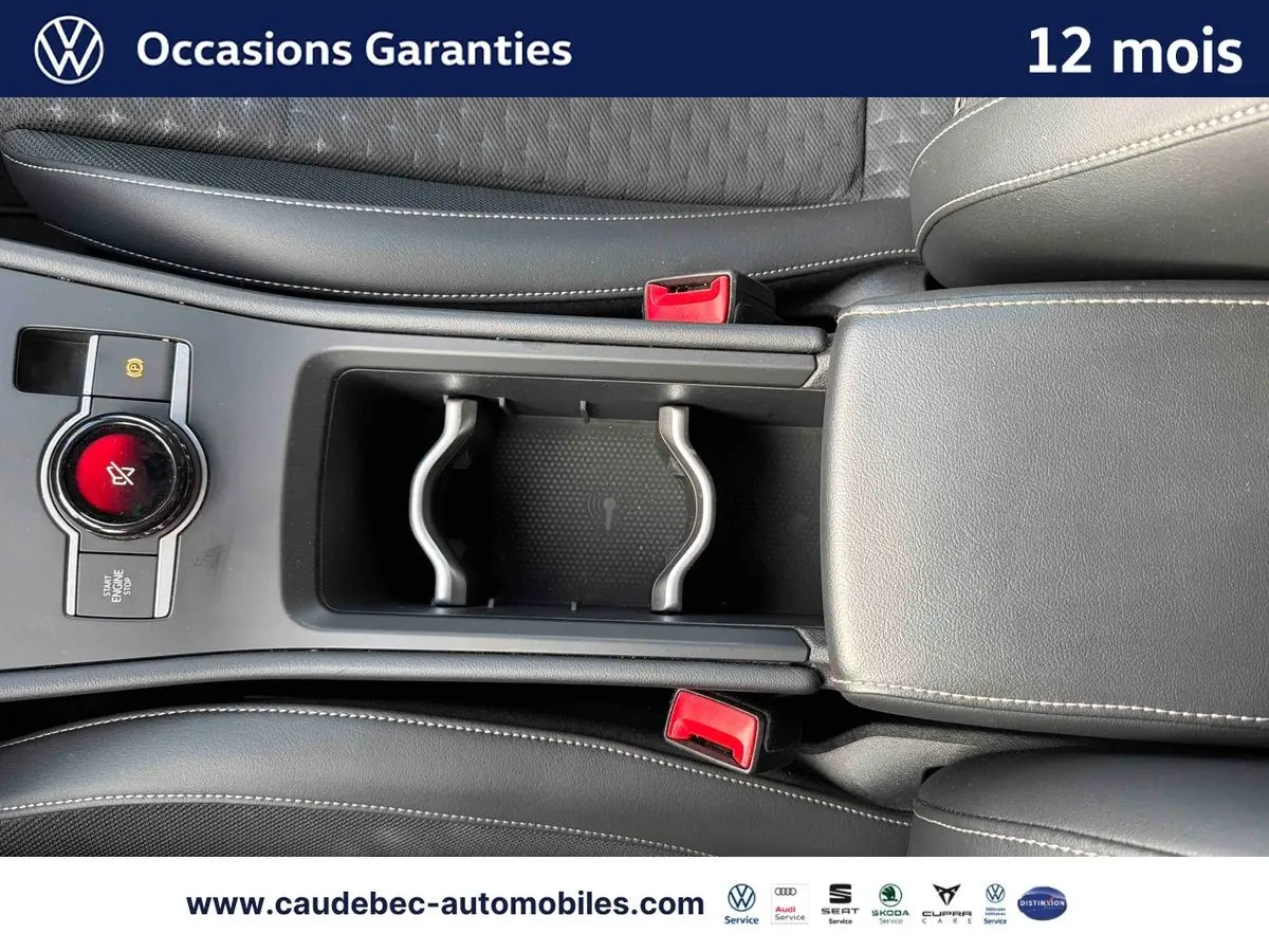 Vue rapprochée de la console centrale du Volkswagen T-Roc 2026, avec accoudoir cuir noir et bouton Start/Stop rouge.