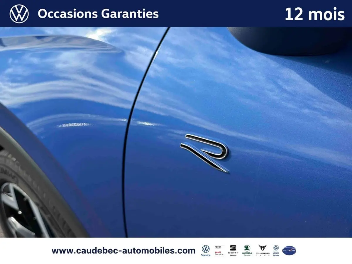 Gros plan sur l'aile avant gauche bleu métallisé du Volkswagen T-Roc avec logo R distinctif.