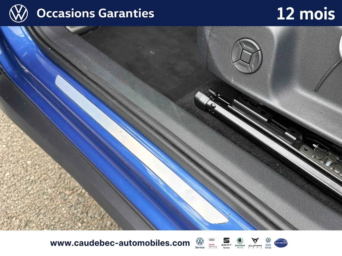 Détail de la porte côté conducteur d’un Volkswagen T-Roc bleu 2026 avec seuil de porte R et intérieur noir.