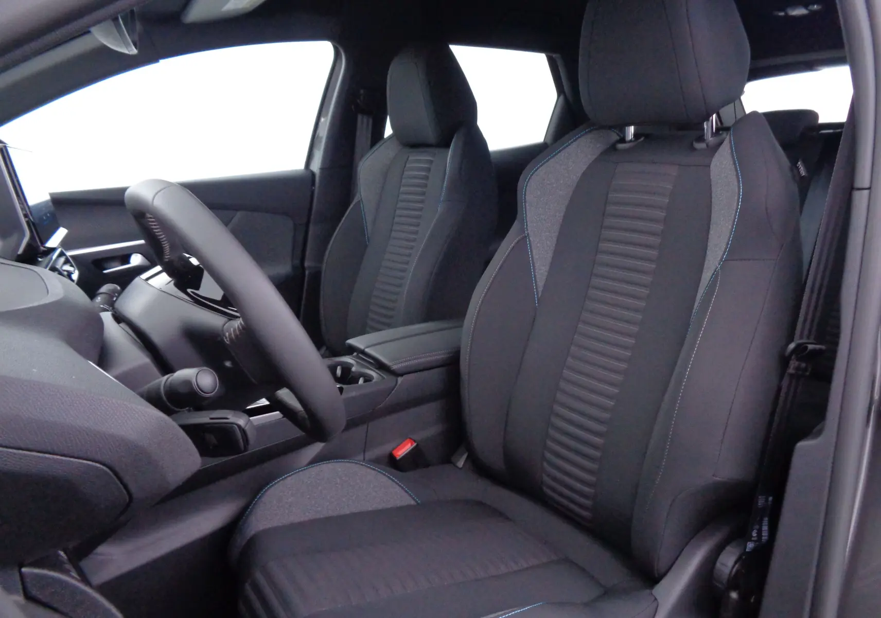 Vue intérieure côté conducteur du Peugeot 3008 2023, sièges noirs avec surpiqûres bleues et volant compact.